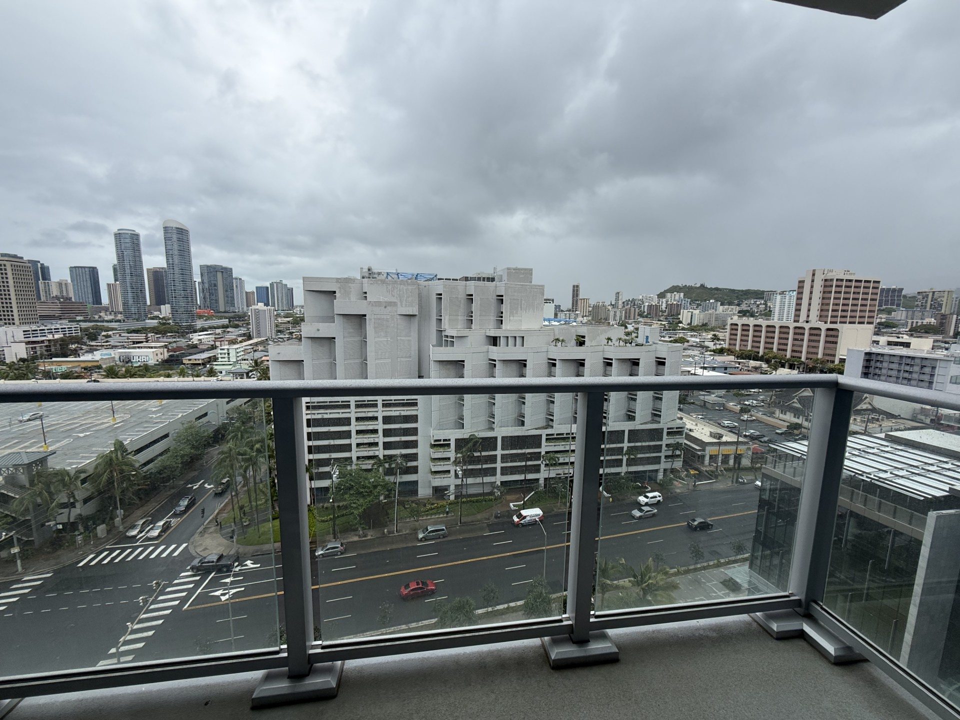 A view from a balcony overlooking a city street with cars and buildings.